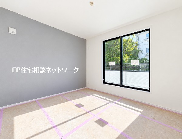 グレーのアクセントクロスが落ち着いた雰囲気を演出する洋室。バルコニーへつながる大きな窓が、室内に明るさと開放感を添えます。
