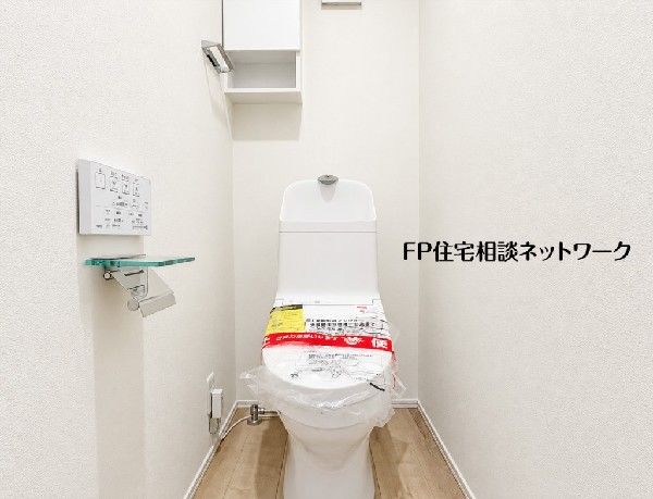清潔感あふれる白を基調としたトイレ。温水洗浄便座付きで快適にご利用いただけます。窓があり換気も良好。手洗いカウンターや収納棚も完備し、機能性にも優れています。