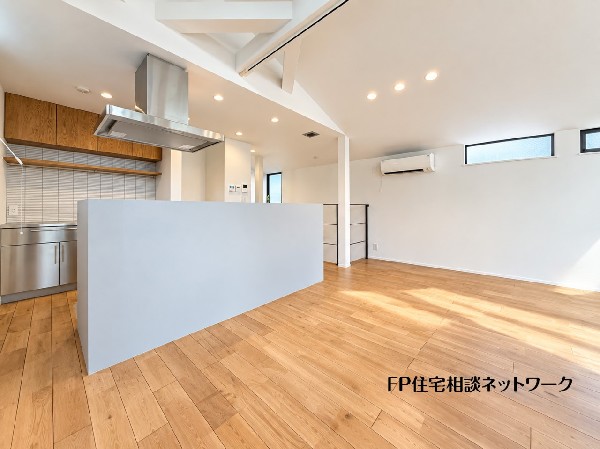 勾配天井が開放感を演出する明るいLDK。木の温もりを感じるフローリングとスタイリッシュなキッチンが調和した、家族が自然と集まる心地よい空間です。