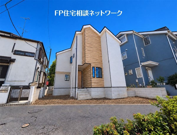 外観:木目調とグレーの外壁が調和した、モダンな外観デザインです。前面道路は舗装されており、住宅街に位置しています。