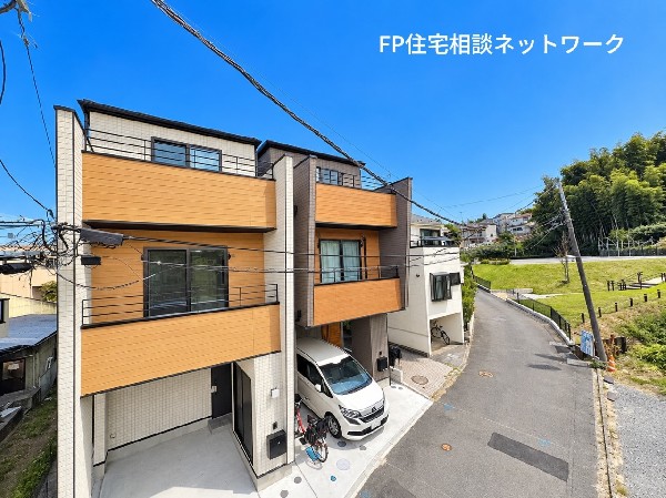 外観:温かみのある木目調の外壁とブラックのアクセントが印象的なデザイナーズ住宅。青空に映えるスタイリッシュな外観と、周囲の緑が調和した開放感のある街並みが魅力です。