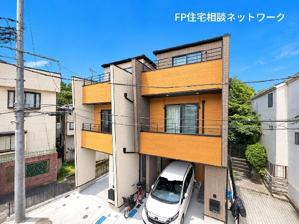 外観:木目調の外壁とブラックの窓枠が美しく調和した、洗練されたデザイナーズ住宅。立体感のあるバルコニーや直線的なフォルムが外観にメリハリを生み、モダンで存在感のある佇まいを演出しています。