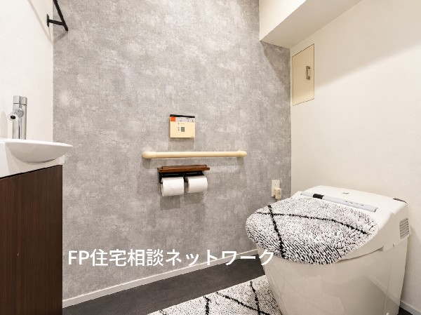 グレーのアクセントクロスが印象的な、落ち着きのあるトイレ空間。手洗いカウンターや収納棚を備え、デザイン性と使いやすさを両立。（家具、小物等は含まれません）